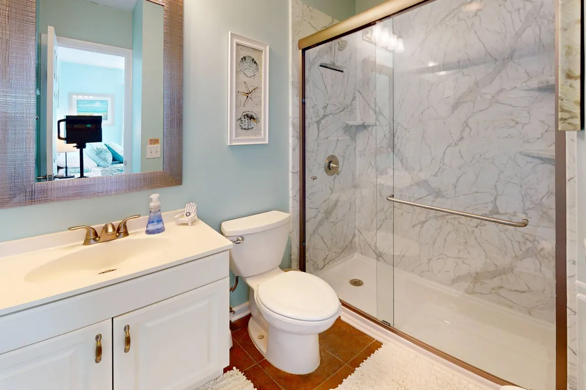 A modern bathroom featuring a bright vanity with sink, a large shower enclosure, and a stylish mirrored frame. The space feels airy and spa-like, perfect for relaxing self-care routines.