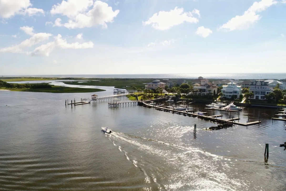 This image displays waterfront houses, a marina with boats docked, and lush greenery. The calm water reflects the tranquil atmosphere, suggesting opportunities for a scenic ferry ride or waterfront dining nearby.